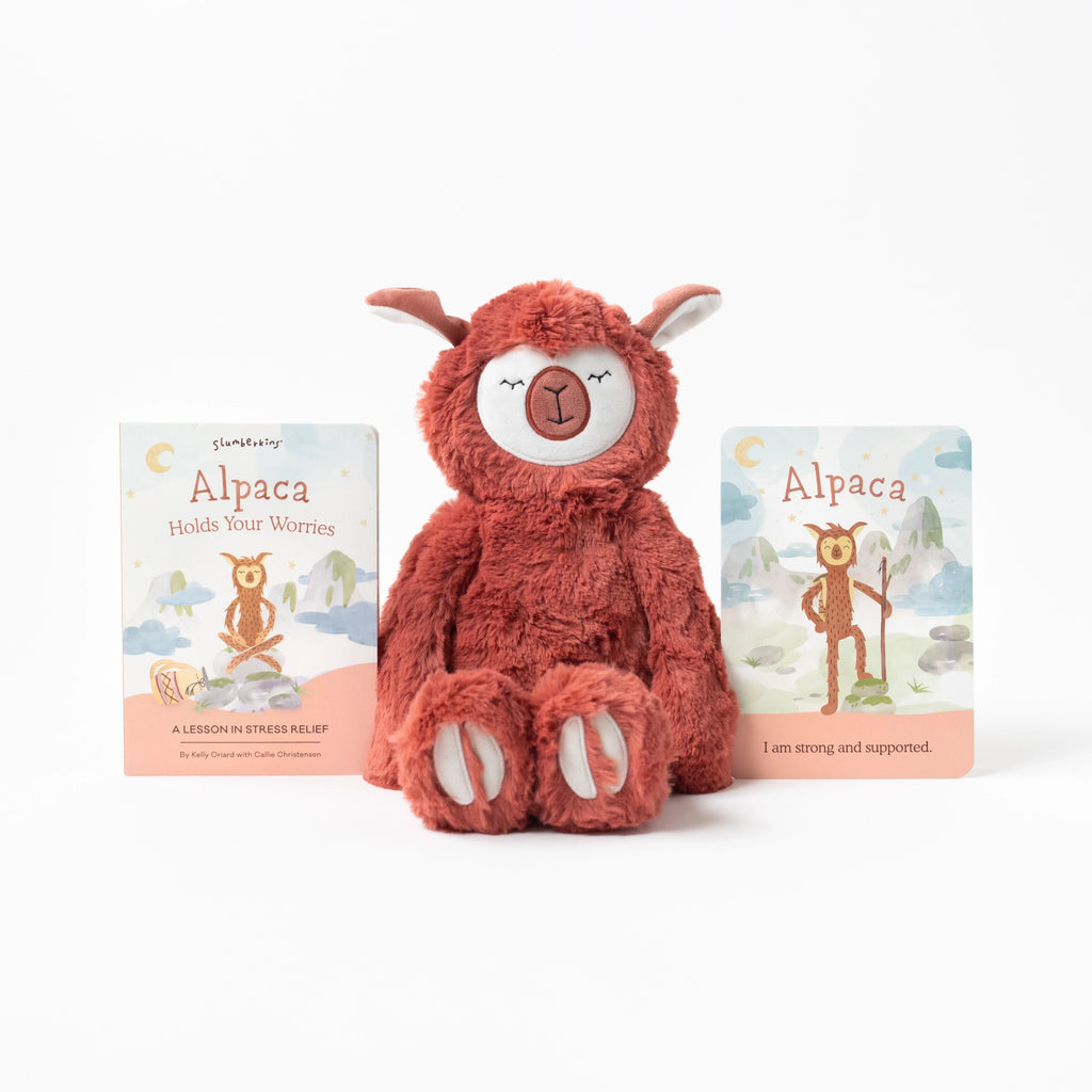 A Slumberkins Alpaca Kin + Lesson Book On Stress Relief, designed for stress relief, sits between two children's books titled "Alpaca Holds Your Worries," with simple and soothing illustrations on a clean, white background.