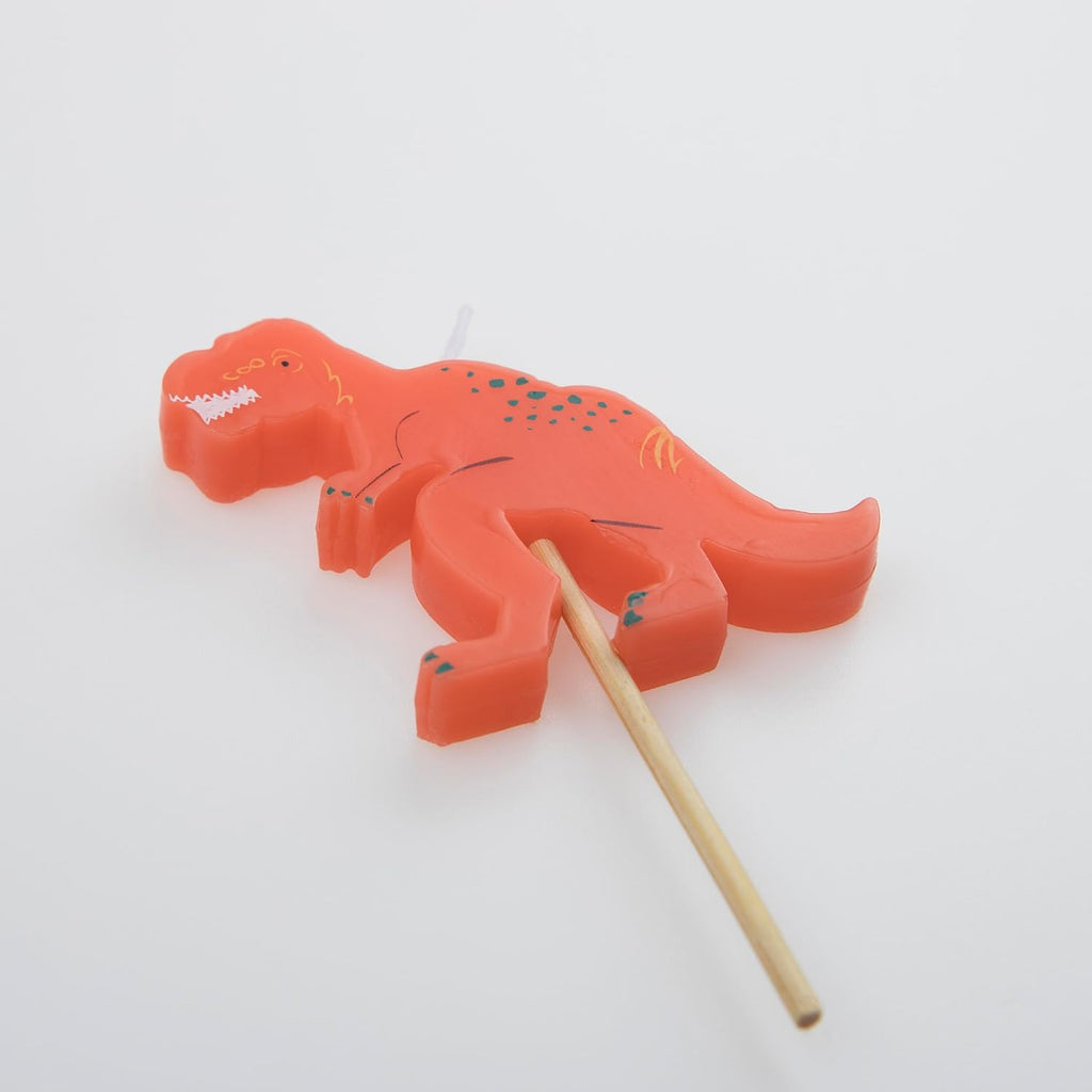 A red Meri Meri Dinosaur Candles with a wooden toothpick embedded at the bottom for stability, set against a plain white background.