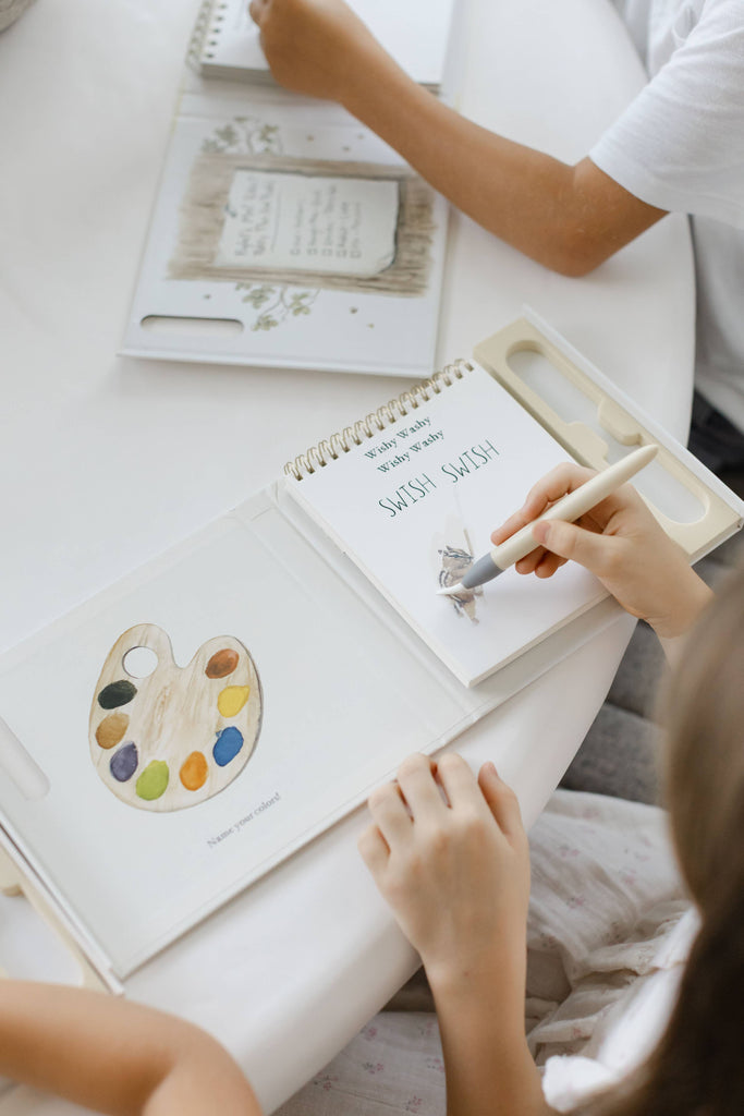 A child uses a water pen to reveal a paint palette illustration in a Winnie-the-Pooh: Pooh’s Birthday Surprise (Water Reveal) book.