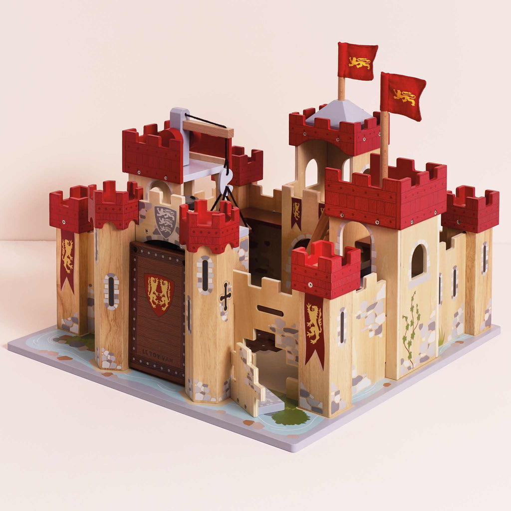 The Lionheart Wooden Castle is crafted from sustainable wood and features red and yellow flags, turrets, a drawbridge, detailed stone patterns, and a decorated base—perfect for inspiring imaginative play.