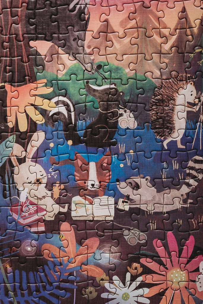 The Mischief Under the Moonlight 300 Piece Puzzle showcases woodland animals—fox, rabbit, hedgehog, raccoon, skunk—reading and exploring in a vibrant forest. Made with recycled materials for an eco-friendly experience.
