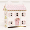 Sophie's Wooden Dolls House features a pastel pink finish, scalloped roof, heart-shaped door, pink shutters, and window flower boxes. This charming wooden dolls house is pictured on a plain white background.