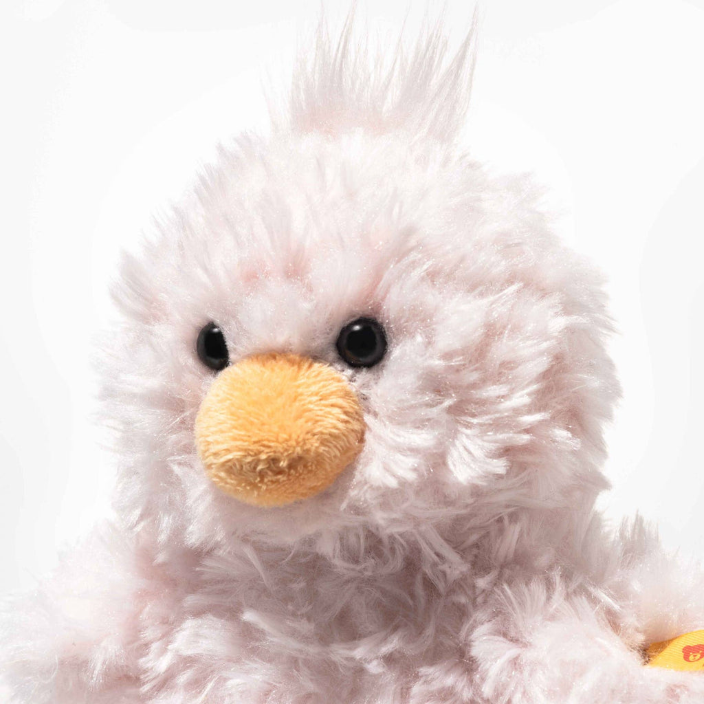 A close-up of the Steiff Pipsy Pink Chick plush, featuring fluffy pale pink fur, black eyes, a yellow beak, textured fur, and a cute tuft of hair on its head.