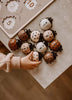 A child’s hand reaches for the My Little Lady Bug Wooden Puzzle, featuring ladybug-shaped wooden pieces in various shades, arranged on a table alongside a Montessori counting toy and a wooden peg puzzle with numbers and animal shapes.
