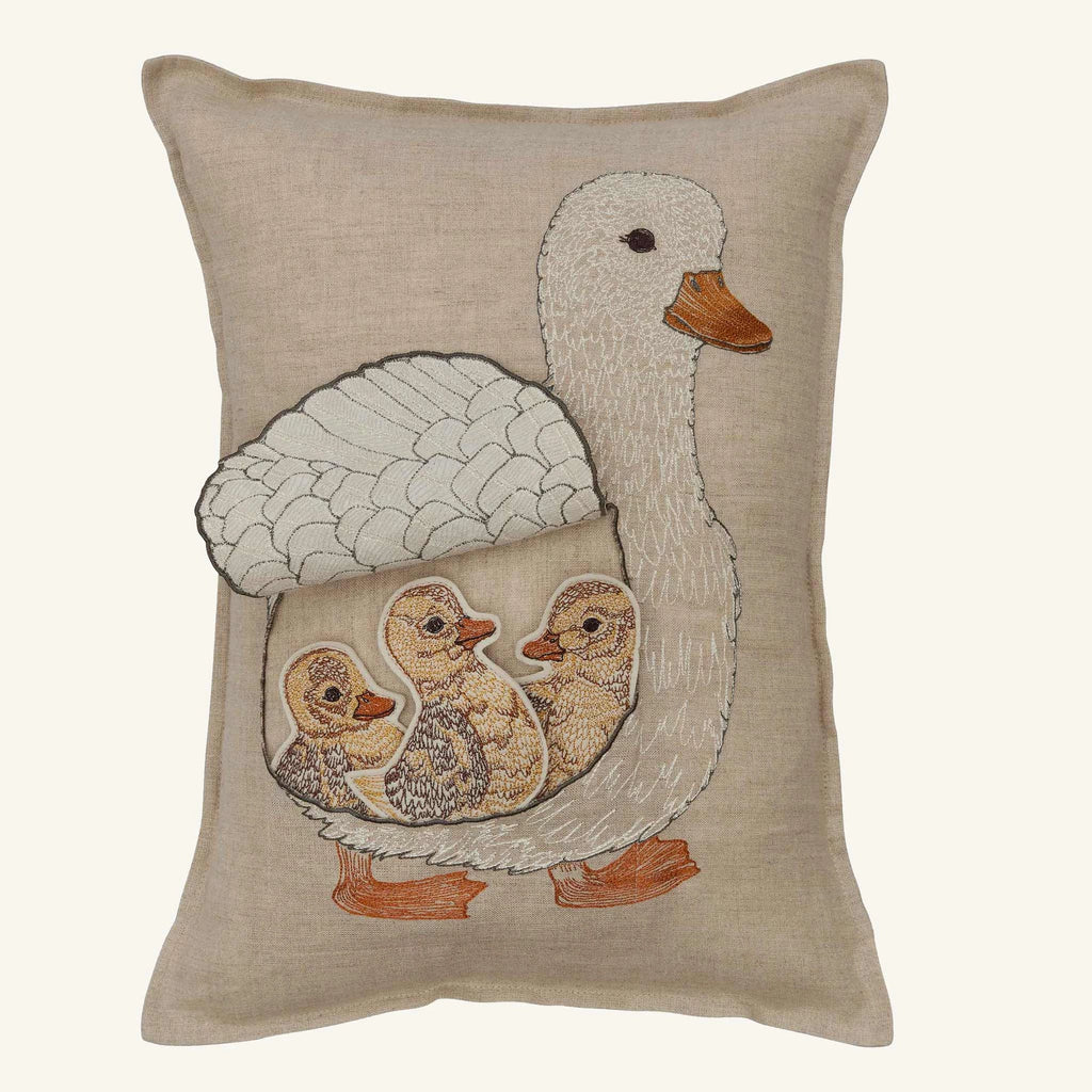 The Coral & Tusk Mama Duck Pocket Pillow in beige features an embroidered white duck and three removable felt ducklings in neutral tones, all nestled under its wing on a plain background.