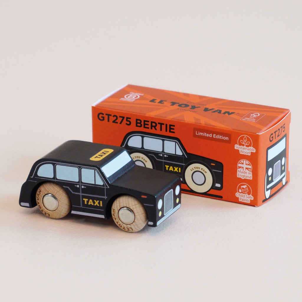 A classic London-style black wooden taxi with “TAXI” on the side, displayed beside its orange and white box labeled “No. 45 GT275 Bertie | Made in England.” The packaging showcases car graphics and highlights its limited edition status.