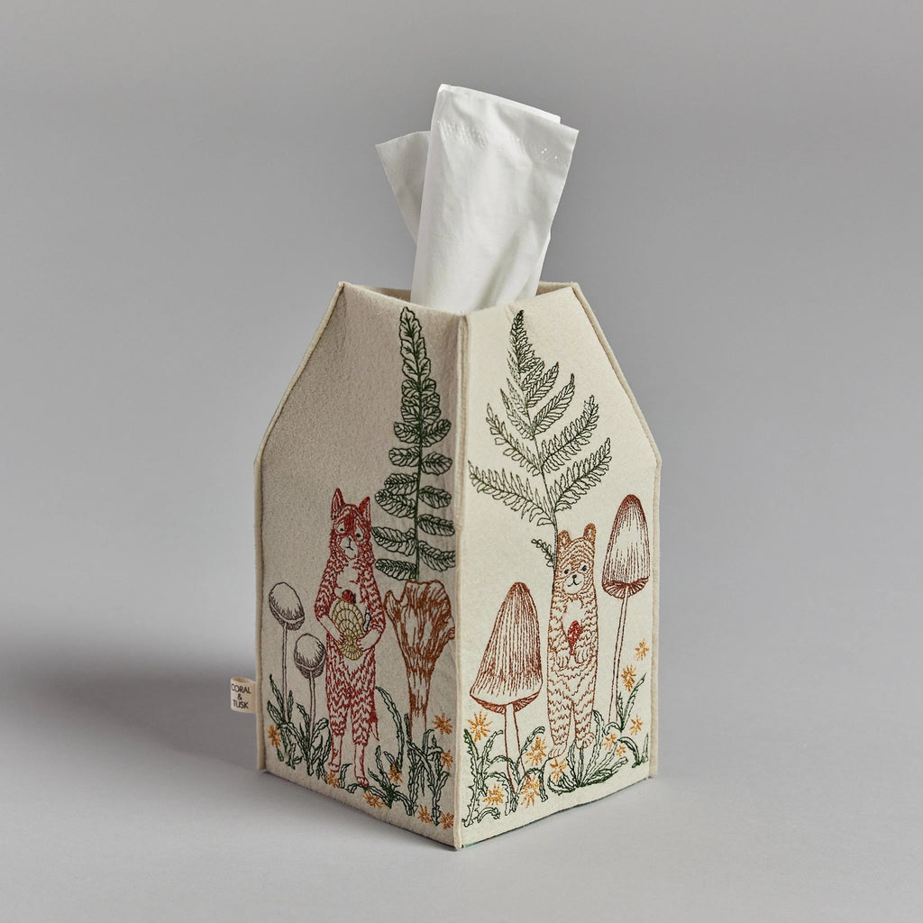 A Coral & Tusk Mushrooms and Ferns tissue box cover shaped like a house and adorned with embroidered woodland motifs including a deer, mushrooms, and ferns on a beige background.