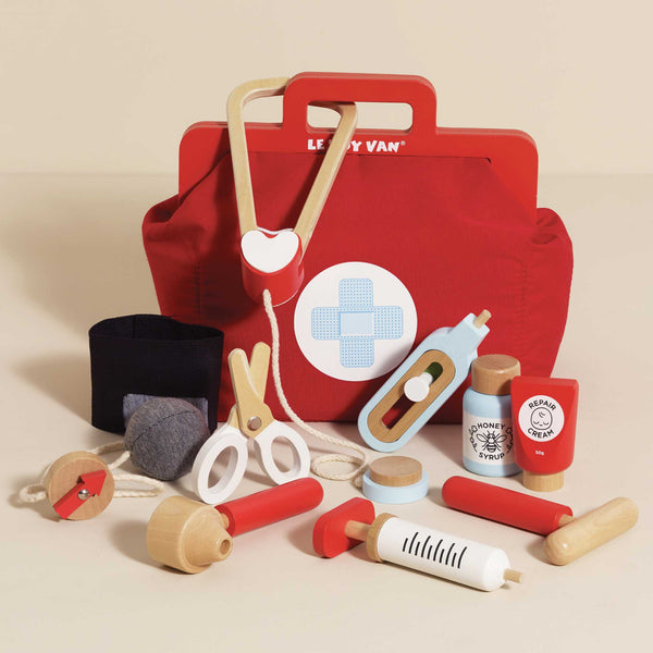 The Pretend Play Vintage Doctor Set features a red toy doctor’s bag with a white and blue cross, plus wooden medical tools—stethoscope, scissors, syringe, medicine bottles, thermometer—ideal for kids’ doctor or nurse role play.