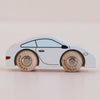 A No. 16 GT90 Poppy, a small white wooden sports car with simple black detailing and wooden wheels, made in the United Kingdom, photographed on a light, neutral background.