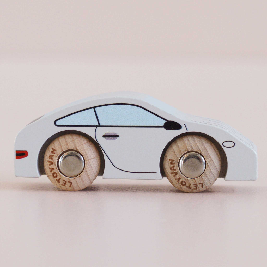 A No. 16 GT90 Poppy, a small white wooden sports car with simple black detailing and wooden wheels, made in the United Kingdom, photographed on a light, neutral background.