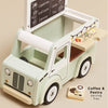 The Mobile Café Van is a vintage-style toy coffee truck with a menu sign, pull-out tray featuring coffee and pastry illustrations, and wooden coffee-themed pieces for play. Made from FSC-certified wood. Tray text: “Coffee & Pastry Serving Tray.”.
