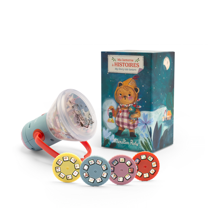 The Moulin Roty Storybook Lantern - The Minouchkas is a children’s projector toy with a red handle, five story reels, and a decorative box featuring an illustrated bear under the night sky—a magical bedtime storyteller.