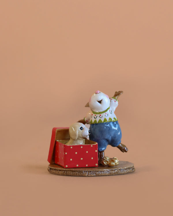 The Wee Forest Folk Tiny Collectible - Christmas Critter features a hand sculpted mouse in blue overalls next to a red polka dot gift box with a puppy inside—a charming piece for any miniatures or Wee Forest Folk collection.