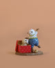 The Wee Forest Folk Tiny Collectible - Christmas Critter features a hand sculpted mouse in blue overalls next to a red polka dot gift box with a puppy inside—a charming piece for any miniatures or Wee Forest Folk collection.