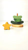 The Handmade Wooden Stacking Toy Green Christmas Tree features a green tree with a brown trunk and an engraved base reading “Atticus,” shown beside a yellow wooden star—ideal for eco-friendly, Montessori-inspired play.