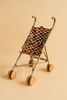 The Konges Sloejd Doll Stroller - Heart Kisses is a small beige stroller with double wheels and a fabric seat featuring a colorful heart pattern, shown against a solid light beige background.