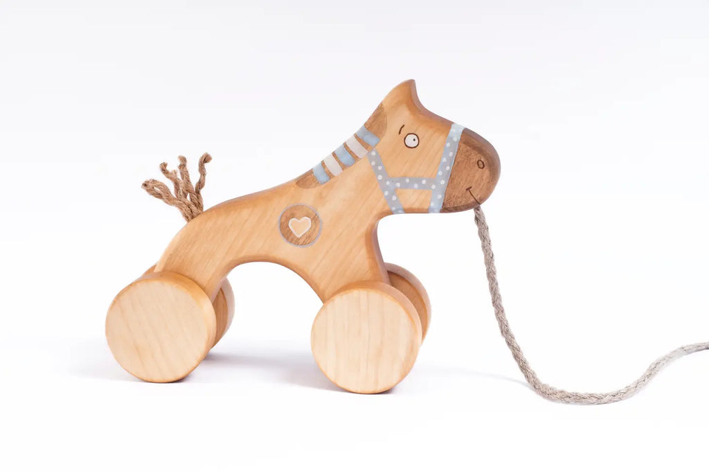 A *Handmade Wooden Horse Pull Toy | Blue* stands against a white background. The horse pull toy features painted details, including a heart on its body and stripes on its face and neck. A string is attached to the horse's front, likely for pulling.