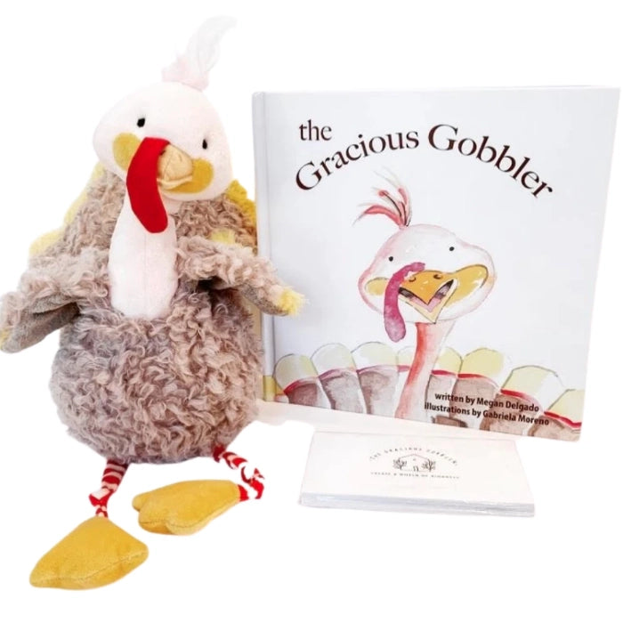 A plush turkey toy with a red and white hat, striped legs, standing next to The Gracious Gobbler Bundle: Children's Book, Plush and Cards, embodies a