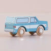 A blue-and-white wooden SUV toy car, crafted in England and named “No. 31 GT170 Chuck,” features black windows, wooden wheels labeled “Le Toy Van,” and sits against a light pink background—perfect for igniting off-road adventures in imaginative play.