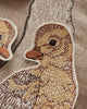 Close-up of a fabric patch on the Coral & Tusk Mama Duck Pocket Pillow, showcasing a finely embroidered duckling with brown and beige stitching, set against an embroidered outline of a larger duck.