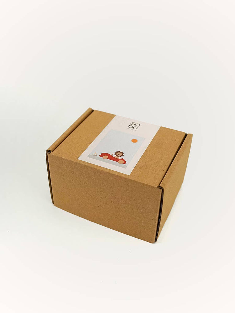 A small brown cardboard box with a sticker on top, featuring the Sabo Concept Car with Lion under a sun, shown against a plain white background.