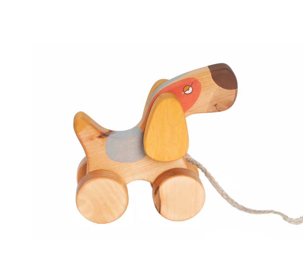 A Handmade Pull Along Terrier Dog Toy, crafted from sustainably harvested birch wood, features a colorful painted design with a long snout, floppy ears, and smooth, rounded wheels. A rope is attached to its front, making it an adorable pull toy dog. The background is white.