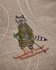 The Coral & Tusk Downhill Skiers Pillow features a raccoon in a green coat, blue mittens, and brown boots skiing on red skis with white trails—an ideal alpine accent for any skier’s decor.