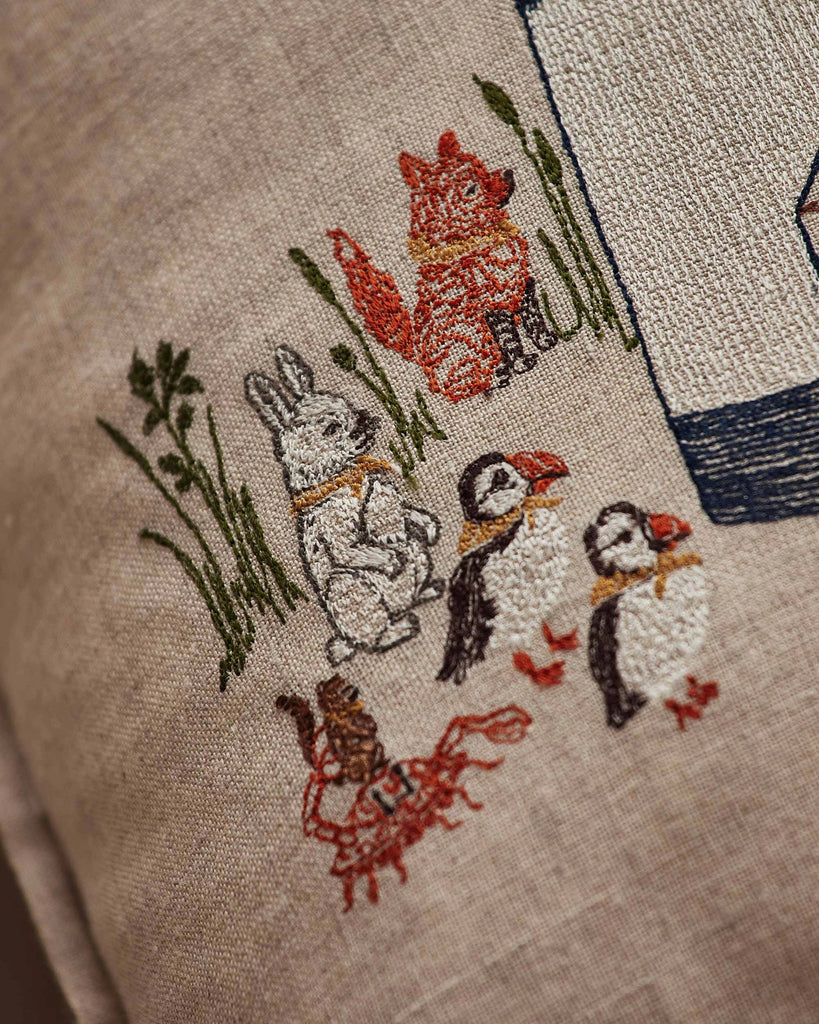 The Coral & Tusk Lighthouse Friends Pocket Pillow features a red fox, rabbit, two puffins, and a crab beside a blue-and-white lighthouse—an ideal nautical accent for your favorite linen pillow cover.