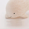 A close-up image of a handmade tiny wooden dolphin figurine, hand-carved from eco-responsible forests, with a smooth texture and a minimalistic design, featuring a small smile.