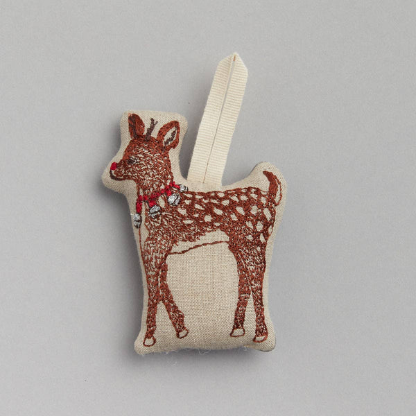 The Rudolph Ornament is a charming fabric decoration shaped like a reindeer, featuring brown embroidery and white spots, presented against a plain background. It includes a loop for hanging, making it perfect for adding festive cheer to your Christmas décor.