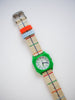The Mini Kyomo Watch x Taxi Brousse - Color Notebook features a green case, white dial, and beige strap with blue, red, and green stripes, plus blue/red loops and silver buckle—shown on a white background.