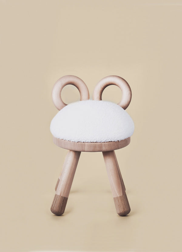 A whimsical Faux Sheep Chair designed to resemble a bunny, featuring European oak legs, a fluffy white faux fur seat, and two round, European oak ears against a soft beige background.