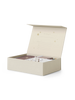 A cream-colored open keepsake box with a hinged lid displays small compartments inside holding various items, including a small toy, a notebook, and a cloth. The inside lid of the Kids Memory Box-The Beginning Of My Life has space for filling in personal information. The box is adorned with star patterns, evoking childhood memories.