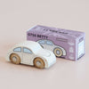 A classic white wooden car with smooth wooden wheels is displayed beside a purple box labeled “No. 9 GT55 Betty | Made in England” and “Limited Edition.” The box showcases an illustration of the car along with certification icons, making this nostalgic toy ideal for imaginative play.