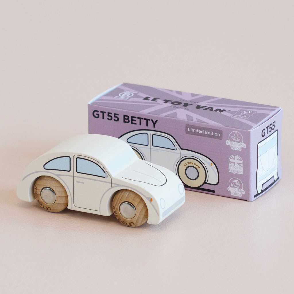 A classic white wooden car with smooth wooden wheels is displayed beside a purple box labeled “No. 9 GT55 Betty | Made in England” and “Limited Edition.” The box showcases an illustration of the car along with certification icons, making this nostalgic toy ideal for imaginative play.