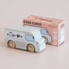 A charming wooden coffee van, adorned with “Café” and a coffee cup illustration on the side, sits before a pink and white box labeled “No. 11 GT65 Coco | Made in England” and “Le Toy Van.” Perfect for imaginative storytelling and thoughtful gifting, this delightful toy inspires creative play.