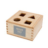 The Natural Shape Sorter Box is an eco-friendly wooden toy with four geometric shapes—circle, square, triangle, and rectangle—in the lid. The side label reads "Wooden Story est. 1969.