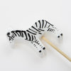 A small, detailed Meri Meri Jungle Animal Candle with black stripes and hooves, positioned atop a thin wooden stick, perfect for a safari party, against a plain white background.