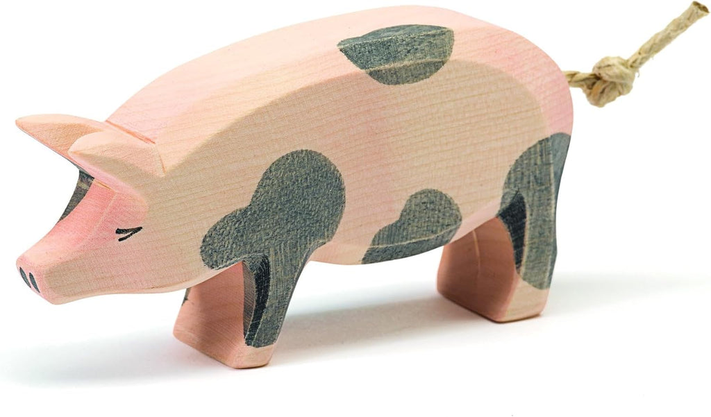 The Ostheimer Spotted Pig - Head High is a handcrafted wooden toy with black spots, simple painted features, and a rope tail, perfect for imaginative play and shown on a white background.