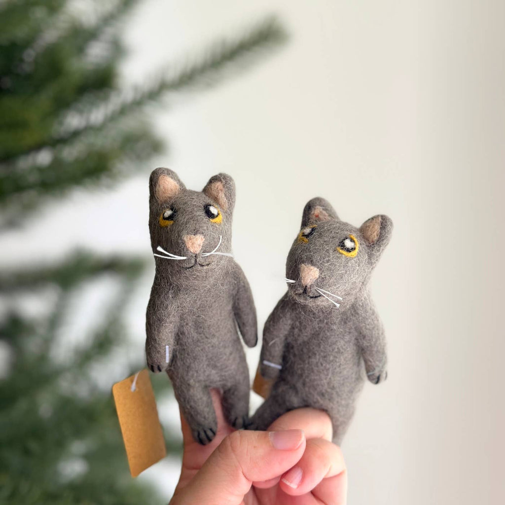 Held gently between fingers are two handmade felt mouse finger puppets. Each mouse features a gray body, small arms, and embroidered details for the eyes, noses, and whiskers. Set against a blurry green tree background, these charming companions perfectly complement the playful Felt Gray Cat Finger Puppet (ships in approximately one week), adding enchantment to any storytelling adventure.