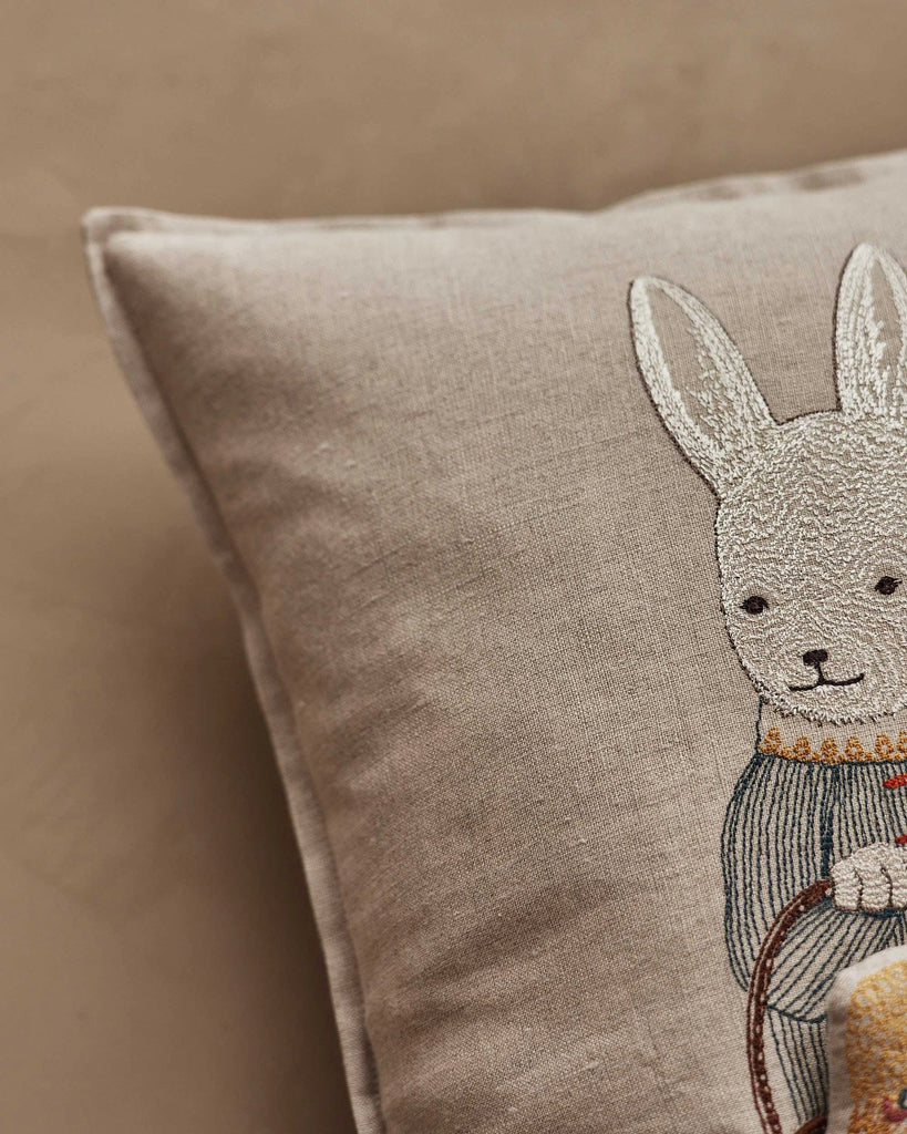 The Coral & Tusk Easter Bunny Pocket Pillow features a beige design with an embroidered white bunny in a blue outfit on a neutral background—an adorable and festive decoration for Easter.