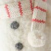 Close-up of the Cuddle + Kind Baby Snowman - Candy Cane, a hand-knit, fuzzy white snowman made from Peruvian alpaca yarn, featuring a cream and red striped scarf with pom-pom—ideal for fans of collectible dolls and baby animals.
