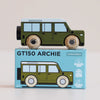 A green wooden 4x4 toy car with black wheels rests atop a blue box labeled “No. 27 GT150 Archie | Made in England.” The box displays an illustration of the same classic toy car, along with icons indicating it is sustainable and child safe—an ideal choice for inspiring imaginative play.