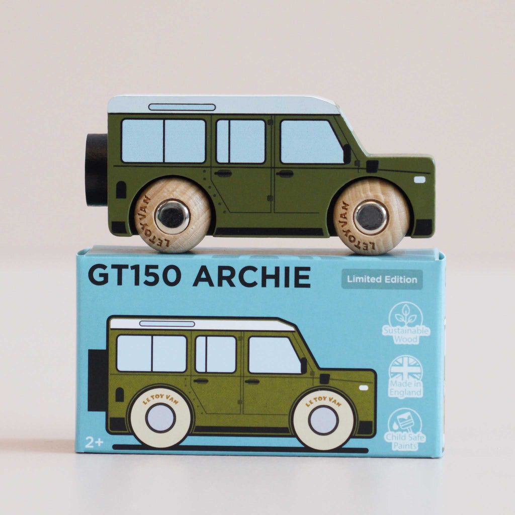 A green wooden 4x4 toy car with black wheels rests atop a blue box labeled “No. 27 GT150 Archie | Made in England.” The box displays an illustration of the same classic toy car, along with icons indicating it is sustainable and child safe—an ideal choice for inspiring imaginative play.