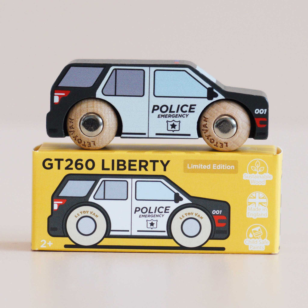 A wooden police SUV from the No. 42 GT260 Liberty collection rests atop its yellow box labeled “GT260 LIBERTY.” The packaging highlights icons for sustainability, child-safe paint, and UK craftsmanship, making it ideal for imaginative storytelling and classic American-inspired play.