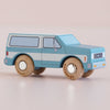 The No. 31 GT170 Chuck, made in England, is a small blue and white wooden SUV with simple details and round wooden wheels, reminiscent of a classic toy car, displayed on a light surface.