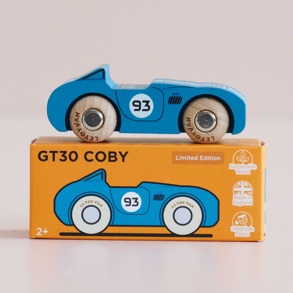 A blue wooden race car marked with the number 93 rests atop an orange box that displays an illustration of the car and text identifying it as the No. 5 GT30 Coby, a sustainable toy made in England and suitable for ages 2 and up.