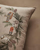 The Coral & Tusk Tree Trimmers Wreath Pillow features embroidered woodland animals—a squirrel, rabbit, and fox—adorned with pine branches and cones on a neutral beige background.