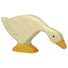 A handcrafted wood toy, this wooden goose figurine is painted in light cream and yellow colors. Made in Europe, the Holztiger Goose, Feeding figure depicts a goose with its head lowered and neck extended, as if pecking at something. It has simple black eyes and minimal detailing on its body.