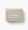 The Delphine Large Embroidered Keepsake Box features ornate gold, blue, and green decorative borders with the word “Keepsakes” displayed in the center, showcased against a white background.